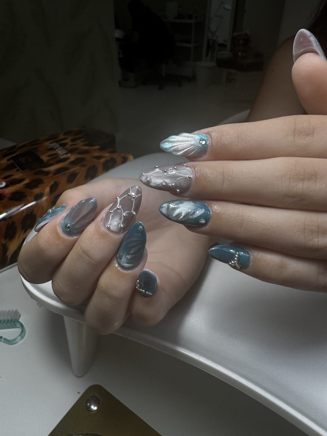 Uñas con efecto ojo de gato azul, conchas en relieve y perlas