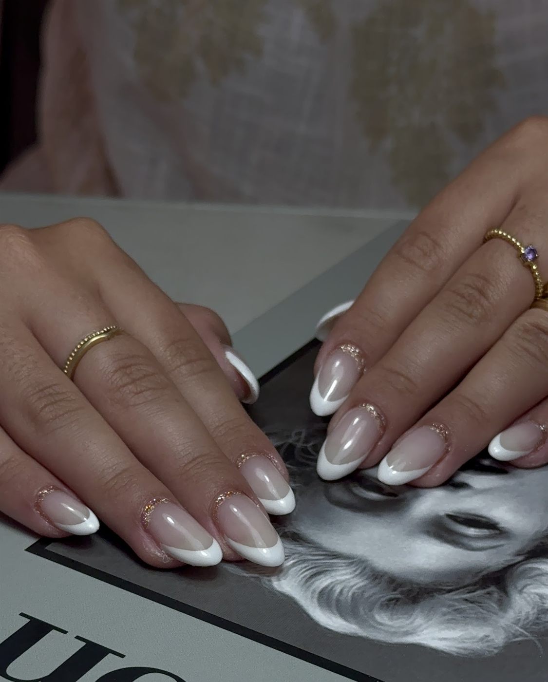 Manicura francesa blanca con una fina línea de purpurina dorada en la cutícula
